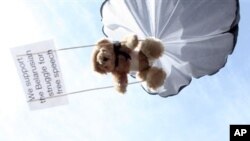 Teddy bear hangs on parachute during protest training for Belarusian airspace intrusion by Swedish human rights activist, Stockholm, July 2012.