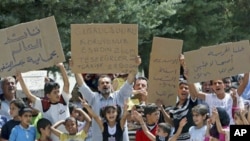 Syrian refugees hold banners - second from left reads 'Protect Jisr al-Shughour from Bashar al-Assad. Thanks to Turkey-Erdogan' - and chant slogans at Altinozu refugee camp in the Turkish border town of Altinozu in Hatay province, June 10, 2011