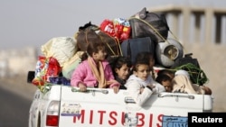 FILE - Children ride on the back of a pick-up truck with their luggage as they flee Saudi-led air strikes in Sanaa, April 6, 2015.