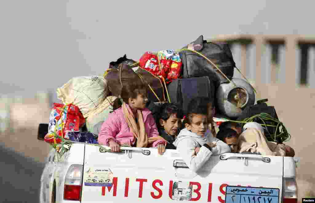 Children ride on the back of a pick-up truck with their luggage as they flee Saudi-led airstrikes in Sana&#39;a, April 6, 2015.