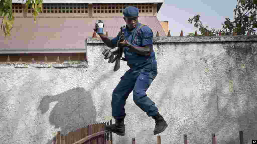 Un policier bondit, en tentant de disperser une foule d&#39;habitants ​en colère après que les parents d&#39;un homme tué par la police, ont été empêchés de l&#39;enterrer conformément à ses croyances musulmanes à Buyenzi, dans la capitale Bujumbura, Burundi mercredi 10 juin 2015