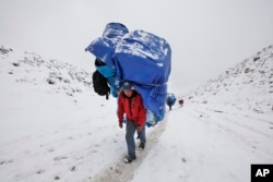 FILE - A porter walks with a massive load towards Everest Base camp near Lobuche, Nepal, March 28, 2016. After two hard years for mountaineers, more than 200 climbers have scaled the daunting mountain in the past 10 days, sending a wave of optimism throug