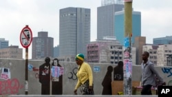 Des gens marchent dans une rue du centre-ville de Johannesburg, en Afrique du Sud, le lundi 16 mars 2020. 