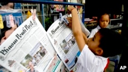 A Cambodian boy hangs up copies of the English-language newspaper, Phnom Penh Post, at the newsstand in Phnom Penh, file photo. 