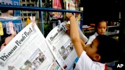 A Cambodian boy hangs up copies of the English-language newspaper, Phnom Penh Post, at the newsstand in Phnom Penh, file photo.