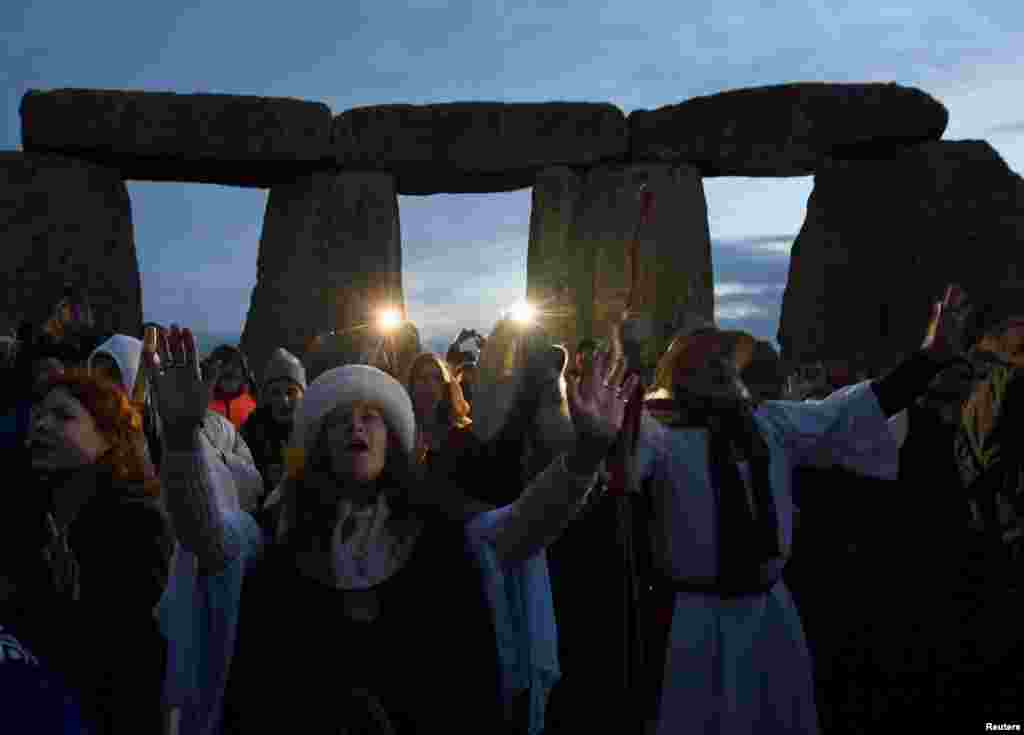 Visitors react at the prehistoric stones of the Stonehenge monument at dawn on Winter Solstice, the shortest day of the year, near Amesbury in southwest Britain.