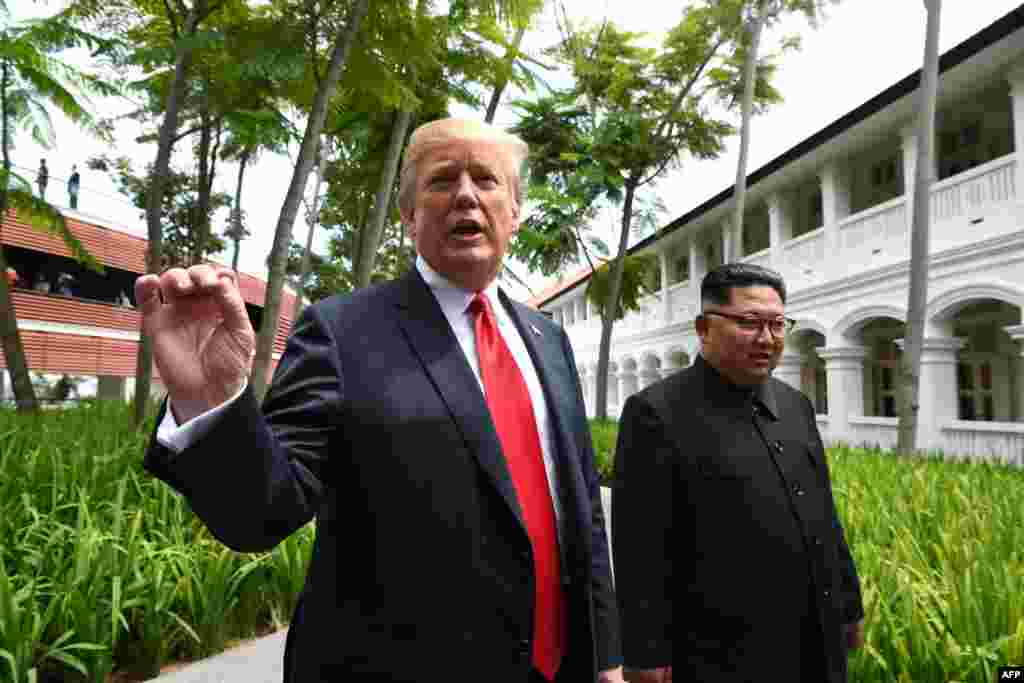 US President Donald Trump (L) speaks to the media as he walks with North Korea's leader Kim Jong Un (R) during a break in talks at their historic US-North Korea summit
