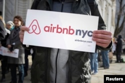 FILE - Supporters of Airbnb stand during a rally before a hearing called "Short Term Rentals: Stimulating the Economy or Destabilizing Neighborhoods?" at City Hall in New York, Jan. 20, 2015.