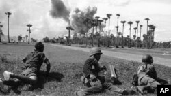 Cambodian soldiers await the end of an airstrike by U.S. planes in the background before advancing toward a palm grove off route 4, south of Phnom Penh, June 13, 1973. (AP photo)