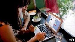 Two women use social networking site Tumblr in a cafe in Hanoi