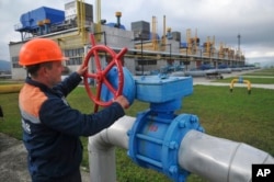 FILE - A worker at a Ukrainian gas station in Volovets, western Ukraine, adjusts a valve, Oct. 7, 2015.