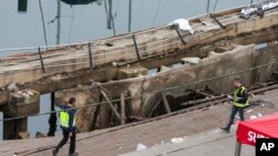 Dos policías trabajan en el lugar donde un día antes colapsó un paseo marítimo en Vigo, España, que dejó más de 300 heridos.