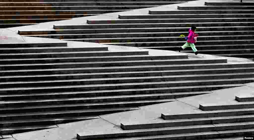 A young girl runs down a set of stairs designed to accommodate wheelchairs in downtown Vancouver, British Columbia, February 7, 2013. 
