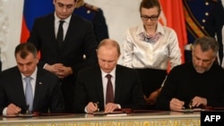 Tổng thống Nga Vladimir Putin, Chủ tịch Quốc hội Crimea Vladimir Konstantionov (trái) và thị trưởng Sevastopol Alexei Chaly ký hiệp ước sáp nhập Crimea vào Nga, ngày 18/3/2014.