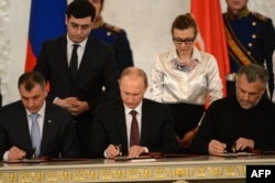 Russia's President Vladimir Putin (C), Crimean parliament speaker Vladimir Konstantionov (L) and Alexei Chaly, Sevastopol's new de facto mayor (R), sign a treaty to make Crimea part of Russia in the Kremlin in Moscow on March 18, 2014.