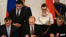 Rossiya prezidenti Vladimir Putin (markazda), Qrim parlamenti spikeri Vladimir Konstantionov (chapda) va Sevastopol shahar meri Aleksey Chaliy Qrim va shaharning Rossiyaga qo'shlishi haqida Kremlda bitim imzolamoqda, Moskva, 18-mart, 2014-yil