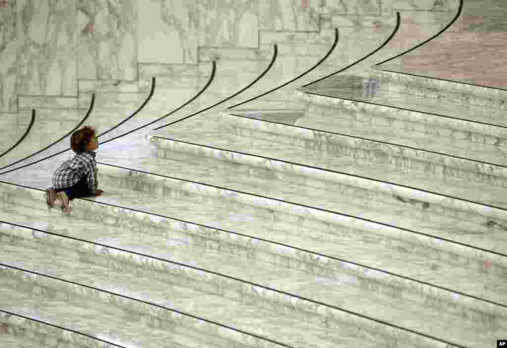 A child looks up as he tries to climb the stairs of the Paul VI Hall prior to the start of Pope Francis&#39; meeting with members of associations that assist blind, deaf and mute persons, at the Vatican.