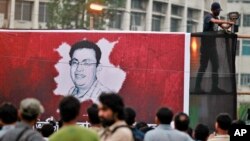 FILE - A Bangladeshi activist sets up a light on a poster displaying a portrait of slain Bangladeshi-American blogger Avijit Roy in Dhaka, Bangladesh, Feb. 27, 2015.