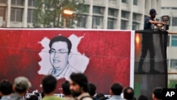 A Bangladeshi activist sets up a light on a poster displaying a portrait of slain Bangladeshi-American blogger Avijit Roy in Dhaka, Bangladesh, Feb. 27, 2015.