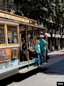 Tourists ride on a cable car in San Francisco, California, April 6, 2016. (M. O'Sullivan/VOA)