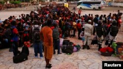 Migrantes hacen fila para abordar un autobús luego de aceptar una oferta del gobierno mexicano para obtener visas humanitarias para transitar por territorio mexicano, en Tapachula, México, el 4 de diciembre de 2021. 