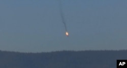 This frame grab from video by Haberturk TV, shows a Russian warplane on fire before crashing on a hill as seen from Hatay province, Turkey, Nov. 24, 2015.