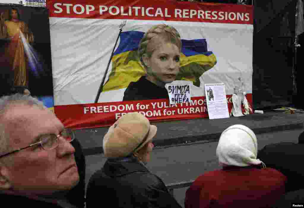 People discuss in front of a poster showing jailed Ukrainian opposition leader Yulia Tymoshenko in central Kyiv. 