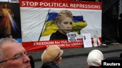 People discuss in front of a poster showing jailed Ukrainian opposition leader Yulia Tymoshenko in central Kyiv, Feb. 22, 2014. 