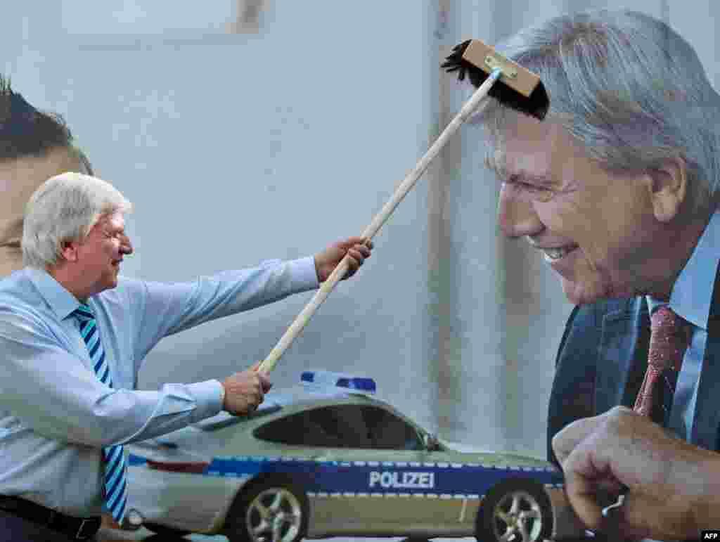 Volker Bouffier, state premier of the western federal state of Hesse and top candidate of the Christian Democratic Union for regional elections, fixes an election poster with his own image in Wiesbaden, western Germany.