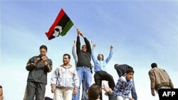 Người dân đứng trên 1 chiếc xe tăng giương cao 1 lá cờ thời kỳ tiền Gadhafi tại Benghazi, Libya, 21/2/2011