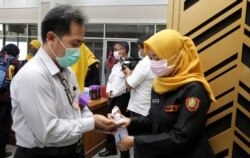 Peserta rapat koordinasi mesti mencuci tangan dengan hand sanitizer dan memakai masker sebelum memasuki ruangan di Pemerintah Kota Surabaya. (Foto: VOA/ Petrus Riski).