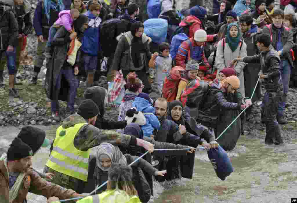 Migrants cross a river, north of Idomeni, Greece, attempting to reach Macedonia on a route that would bypass the border fence. Hundreds of migrants and refugees walked out of an overcrowded camp on the Greek-Macedonian border determined to use a dangerous crossing to head north.