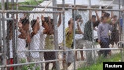 Asylum-seekers look through a fence at the Manus Island detention center in Papua New Guinea, March 21, 2014.