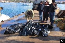 FILE - People check bodies of migrants that were drowned as they were trying to reach Greece, at a port near Izmir, Turkey, Jan. 21, 2016.