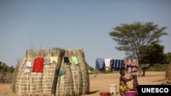 A woman bathes her child next to her hut in Turkana, Kenya. Educating mothers are more likely to seek medical help during pregnancy and childbirth.