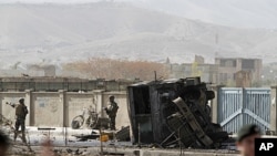 US soldiers, left, stand at the site of a suicide car bomber in Kabul, Afghanistan, October 29, 2011.