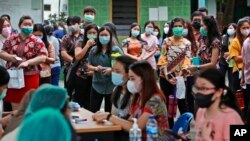 People line up as they wait for their turn to get a shot of the Sinovac COVID-19 vaccine during a mass vaccination at Putri Hijau Military Hospital in Medan, North Sumatra, Indonesia.