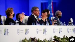 Britain's Alok Sharma, second left, president of the COP26, and Patricia Espinosa, left, UNFCCC executive-secretary applaud during closing plenary session of the COP26 U.N. Climate Summit, Glasgow, Scotland, Nov. 13, 2021.