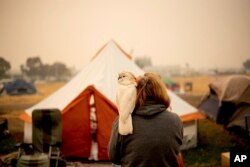 An evacuee of the "Camp Fire," and her pet cockatoo are seen at a makeshift shelter outside a Walmart store in Chico, California, Nov. 14, 2018.