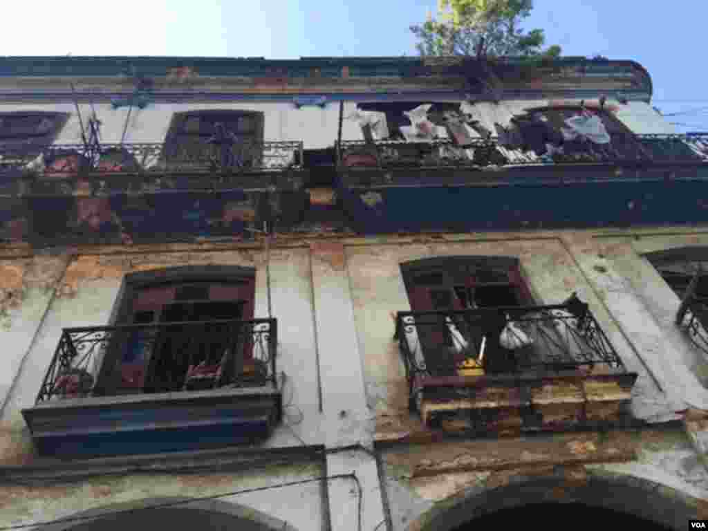 Men stand on the balcony of a house in Havana which is being condemned by the government due to its condition, Aug. 13, 2015. (Celia Mendoza/VOA).