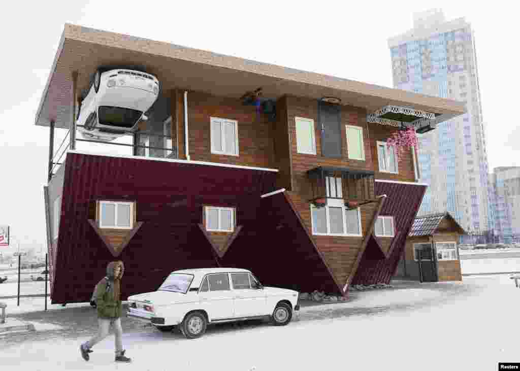 A man passes a house built upside-down in Russia&#39;s Siberian city of Krasnoyarsk, Dec. 14, 2014. The house was constructed as an attraction for local residents and tourists.