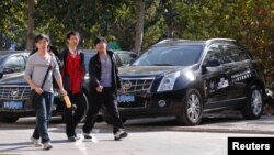 People walk past Cadillac cars outside a dealership in Beijing.