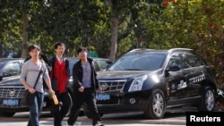 人们走过北京一家汽车销售行旁边的外国轿车