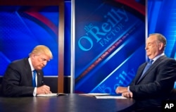 FILE - Republican presidential candidate Donald Trump, left, signs his book for Bill O'Reilly, right, during his appearance on Fox's news talk show "The O'Reilly Factor" in New York, Nov. 6, 2015.