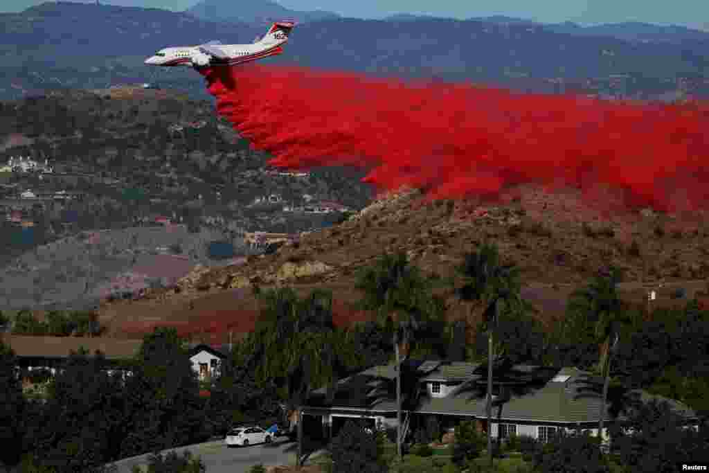An aircraft drops fire retardant as firefighters take advantage of light winds to attack the Lilac Fire, a fast-moving wildfire in Bonsall, California, Dec. 8, 2017.