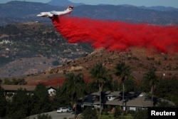 Avion ispušta protivpožarnu smešu dok se vatrogasci koriste prednost slabijeg vetra da bi se borili protiv požara Lilak, brzo širuće vatrene stihije u Bosalu, Kalifornija, 8. decembra 2017.