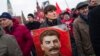 FILE - Communist party supporters hold portraits of Stalin as they line up to place flowers on his grave in Red Square, outside the Kremlin wall, to mark the 64th anniversary of his death in Moscow, Russia, March 5, 2017. Polls show that Stalin is being increasingly seen by Russian as less a villain and more of an "effective manager" and a symbol of Soviet-Russian power.