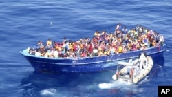 In this photo provided by the Italian Navy, migrants are approached by an Italian Navy dinghy boat in the Mediterranean sea, Aug. 22, 2015. 