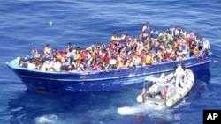 In this photo provided by the Italian Navy, migrants are approached by an Italian Navy dinghy boat in the Mediterranean sea, Aug. 22, 2015. 
