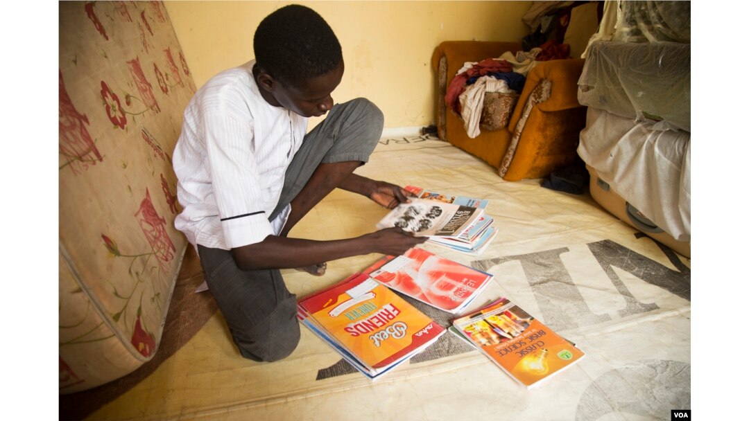 Abdulkadir Abdullahi, 17, looks through his brand-new textbooks in Maiduguri, Nigeria, October 2016. (C. Oduah/VOA)
